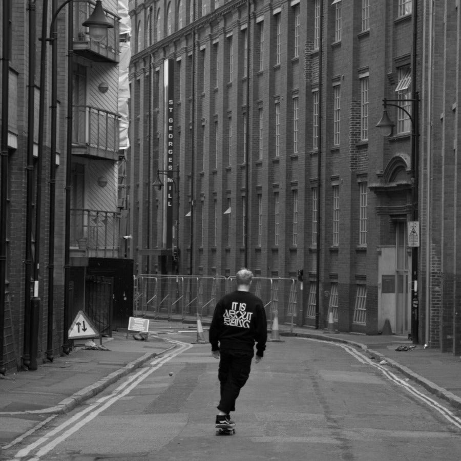 Person walking down a narrow street between tall buildings
